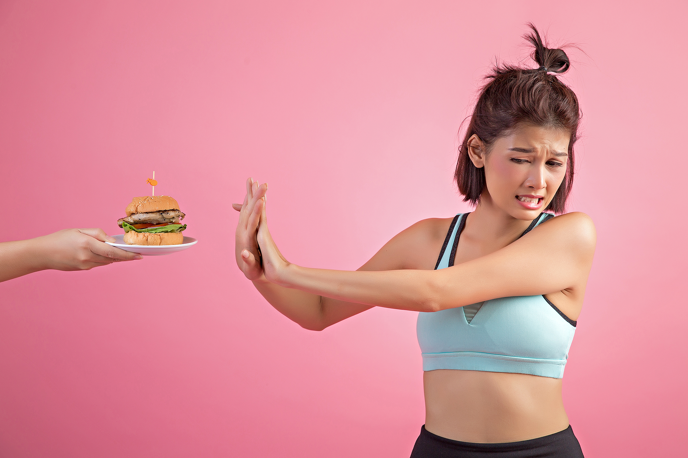 Asian women refuse fast food because of slimming on pink background