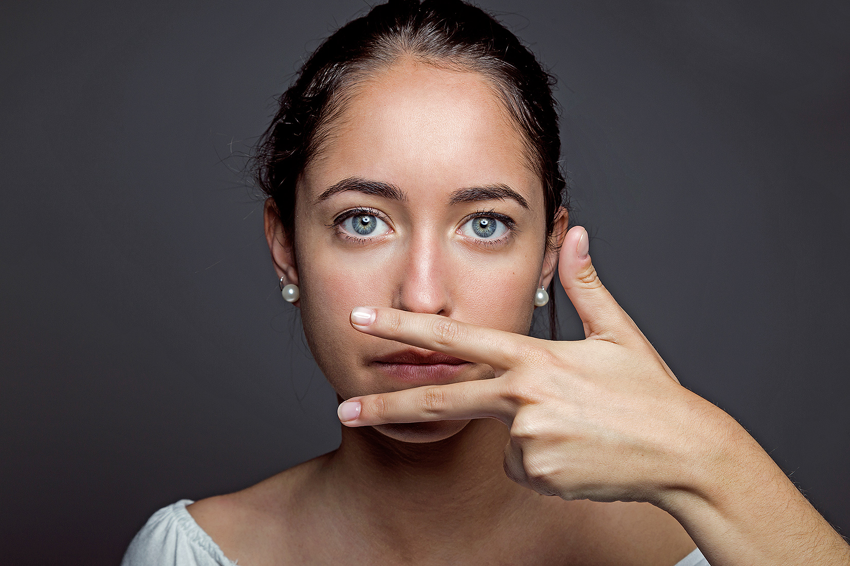 Portrait of beautiful young woman covering her mouth with hand. Isolated.