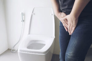 Woman holding hand near toilet bowl - health problem concept